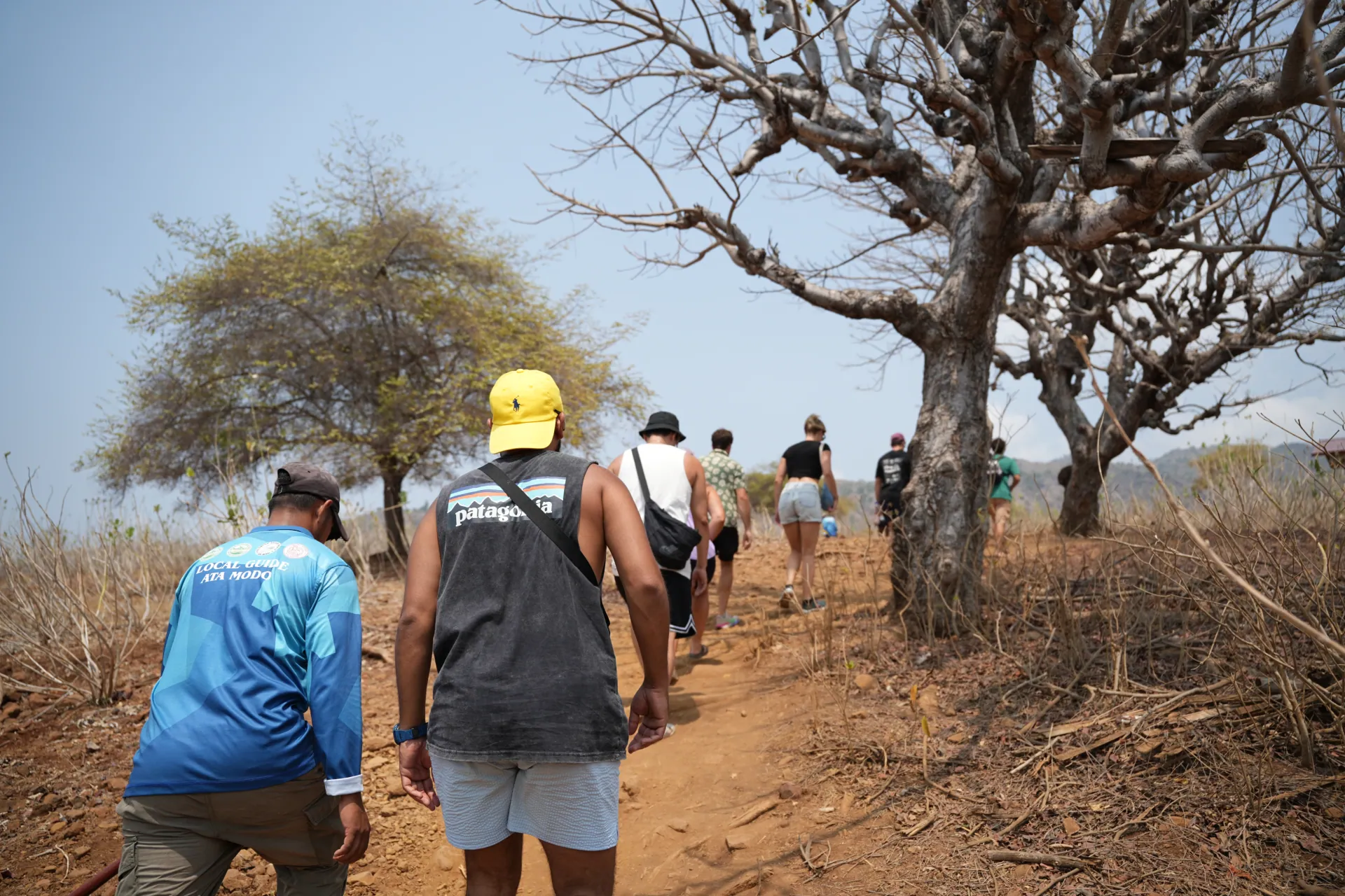 Visitors walking with a park ranger along a dry forest trail in Komodo National Park