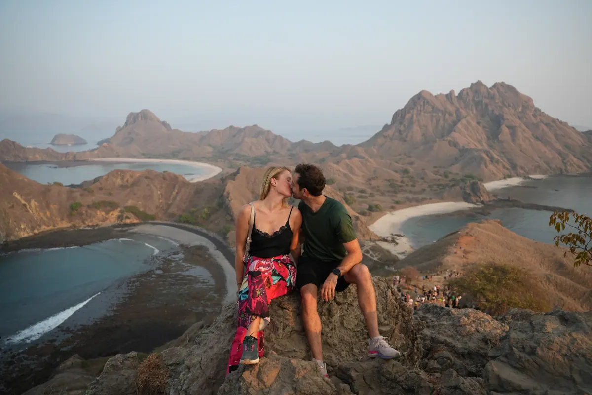 Couple overlooking the multi-coloured bays from the Padar Island viewpoint in Komodo National Park